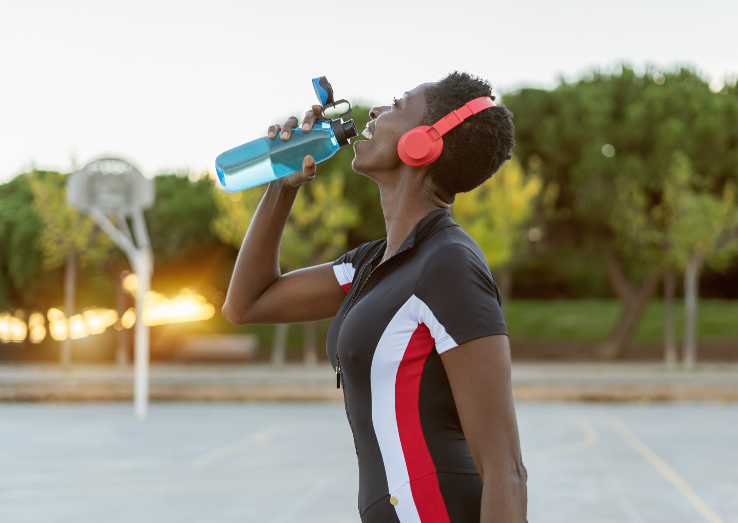 Fitness woman relaxing, drinking water after training workout