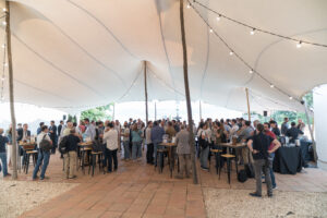 Guests networking at an outdoor corporate event under a large event tent